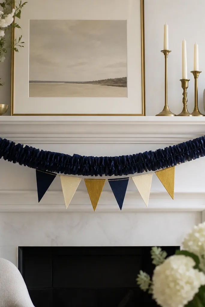 A mantel with a navy crepe paper garland draped in a gentle wave. Small mini flags in navy, cream, and gold hang from the garland near the center.