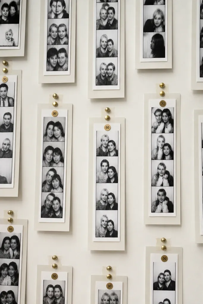 A wall covered in black-and-white photo strips in taped frames. Each strip has a small "30" label at the top and a few gold pushpins.