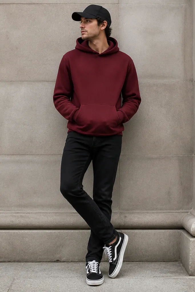 A burgundy hoodie worn with black jeans, paired with a black baseball cap. The hoodie has a front pocket and the cuffs sit at the wrist. Shoes are black and white sneakers.