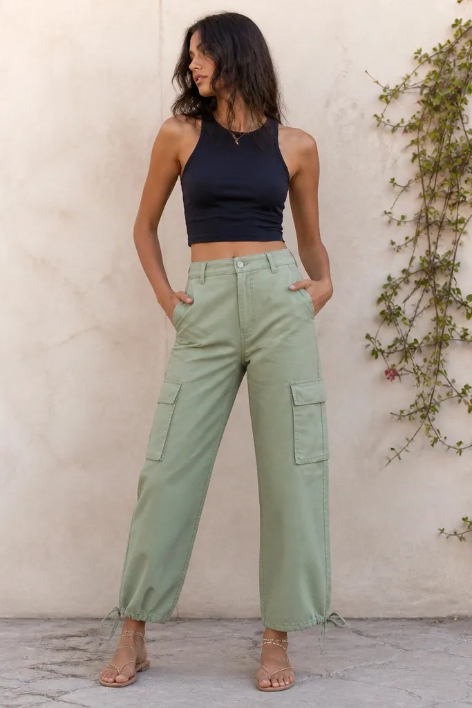 Sage green cargo pants with a navy cropped top. The top sits at the waistband and shows a small gap at the midriff. Nude flat sandals and gold anklets.